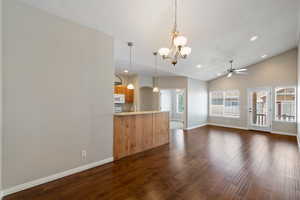 Unfurnished living room featuring a chandelier, dark wood-style floors, vaulted ceiling, ceiling fan, and recessed lighting