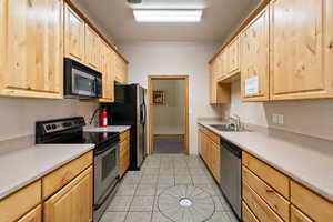 Kitchen featuring stainless steel appliances, light brown cabinets, and light tile patterned flooring