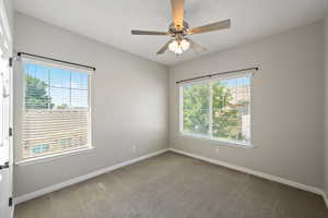 Carpeted spare room with baseboards and ceiling fan