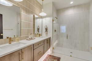 Bathroom featuring a shower stall, double vanity, and recessed lighting