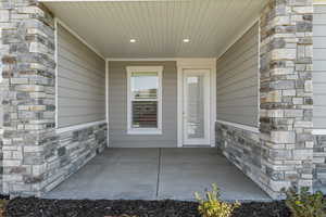 Doorway to property featuring stone siding and a patio area