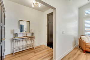 Corridor featuring light wood-style flooring and a chandelier