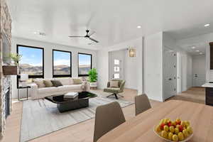 Living room with light wood finished floors, recessed lighting, ceiling fan, a mountain view, and a stone fireplace