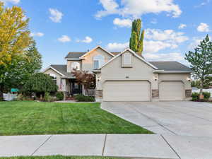 Traditional home featuring stucco siding, a garage, driveway, and stone siding