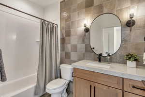 Bathroom featuring tile walls, shower / tub combo with curtain, vanity, backsplash, and tile patterned floors