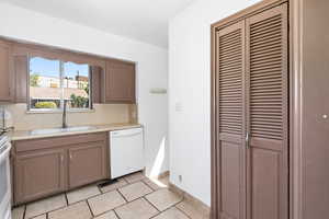 Kitchen with white appliances, light countertops, decorative backsplash, and light tile patterned floors