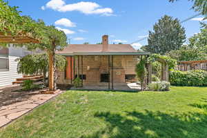 Back of property with a patio area, a chimney, brick siding, a yard, and roof with shingles
