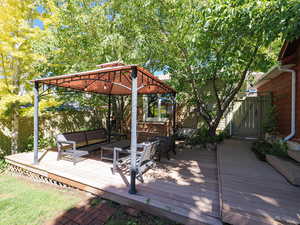 Wooden deck featuring a gazebo, a gate, and outdoor lounge area