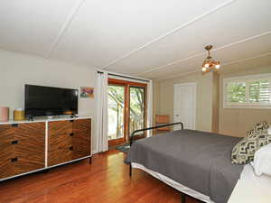 Bedroom with wood finished floors, access to exterior, and a chandelier