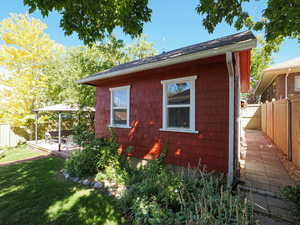 View of home's exterior featuring a fenced backyard, a shingled roof, and an outbuilding