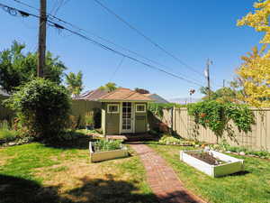 Fenced backyard with a garden, an outbuilding, and a deck