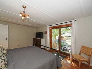 Bedroom with access to exterior, wood finished floors, and a chandelier