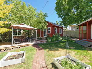 View of yard featuring a gazebo, a deck, a vegetable garden, and an outbuilding