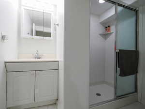 Bathroom featuring a stall shower, vanity, and light tile patterned flooring