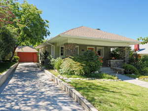 Bungalow with covered porch, stone siding, a front lawn, and an outdoor structure