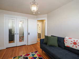 Living room with wood finished floors, french doors, and a chandelier