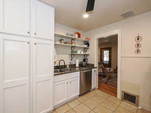 Kitchen with white cabinets, open shelves, light tile patterned floors, dishwasher, and dark stone countertops
