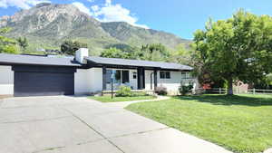 Ranch-style home featuring an attached garage, covered porch, a chimney, a mountain view, and driveway
