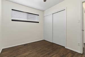 Unfurnished bedroom with dark wood-style flooring, a closet, and ceiling fan