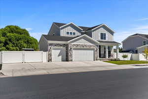 Craftsman-style house featuring a gate, driveway, a garage, covered porch, and board and batten siding