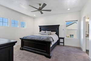 Bedroom with light colored carpet, a textured ceiling, multiple windows, a ceiling fan, and recessed lighting