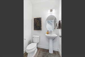 Half bath with toilet and wood finished floors