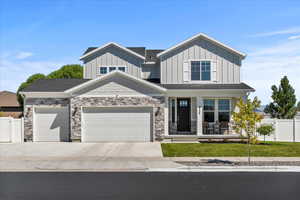 Craftsman-style house featuring covered porch, driveway, board and batten siding, a garage, and stone siding