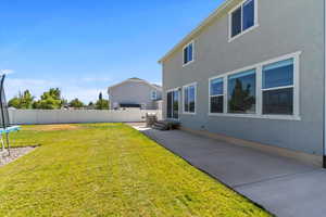 Fenced backyard featuring a trampoline and a patio