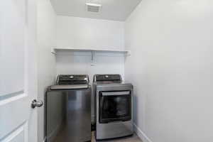 Laundry area featuring a textured ceiling, washer and dryer, and light wood-style flooring