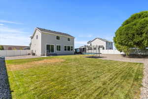 Back of property with a fenced backyard, a trampoline, stucco siding, and a patio area