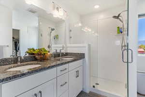 Bathroom with a stall shower, a walk in closet, and double vanity