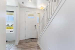 Entryway with light wood finished floors, a textured ceiling, and stairway