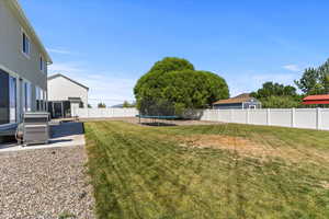 Fenced backyard with a trampoline and a patio