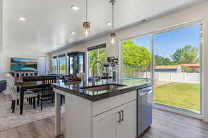 Kitchen featuring hanging light fixtures, white cabinetry, open floor plan, dark stone counters, and a textured ceiling