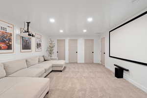 Cinema room with light colored carpet and recessed lighting
