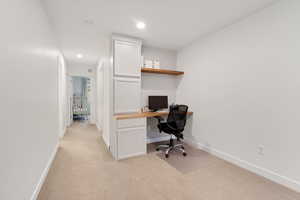 Office with light colored carpet, recessed lighting, and built in desk