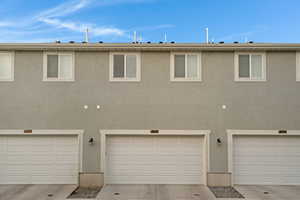 Rear view of property featuring stucco siding and concrete driveway