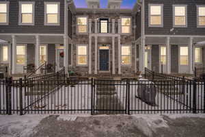 View of front facade with a gate, a fenced front yard, stone siding, and a balcony