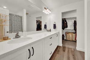 Bathroom with a spacious closet, double vanity, light wood-style flooring, and a shower with shower curtain