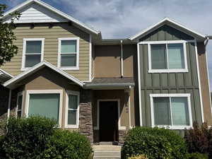 View of front of home featuring a front lawn, board and batten siding, and stone siding