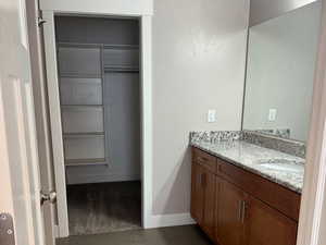 Full bathroom featuring vanity, a walk in closet, a textured ceiling, and lighter colored floors.