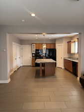Kitchen with recessed lighting, beautiful cabinetry, a large center island, black new or newer appliances, and glass insert cabinets