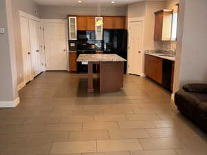 Kitchen featuring recessed lighting, black appliances, decorative light fixtures, a kitchen island.