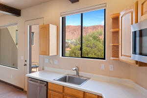 Kitchen featuring light countertops, stainless steel appliances, light brown cabinets, beamed ceiling, and open shelves