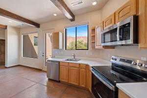 Kitchen featuring stainless steel appliances, light countertops, beam ceiling, recessed lighting, and open shelves