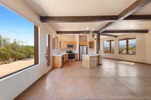 Kitchen featuring light brown cabinets, beam ceiling, light countertops, open floor plan, and appliances with stainless steel finishes