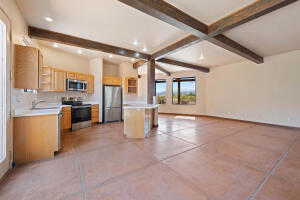 Kitchen with open floor plan, stainless steel appliances, light countertops, concrete floors, and beamed ceiling