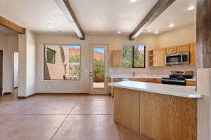 Kitchen with beam ceiling, concrete floors, light countertops, open shelves, and a peninsula