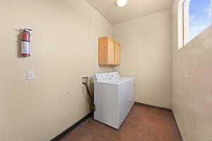 Laundry area with washer / dryer and dark tile patterned flooring