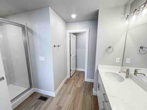 Bathroom featuring a textured ceiling, a shower stall, vanity, and light wood finished floors